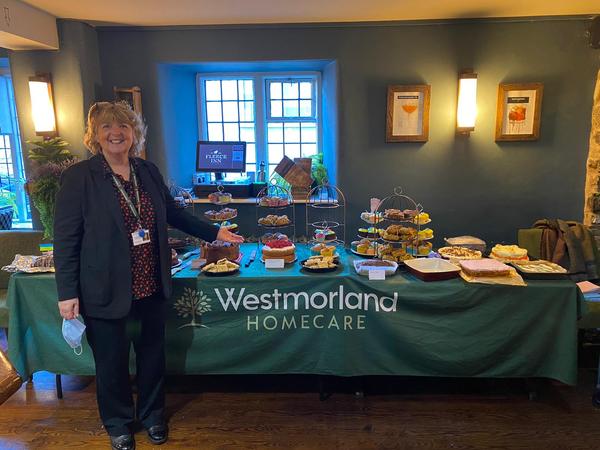 Bernadine Davies, care manager at Westmorland Homecare, with the array of cakes at the coffee morning.jpg